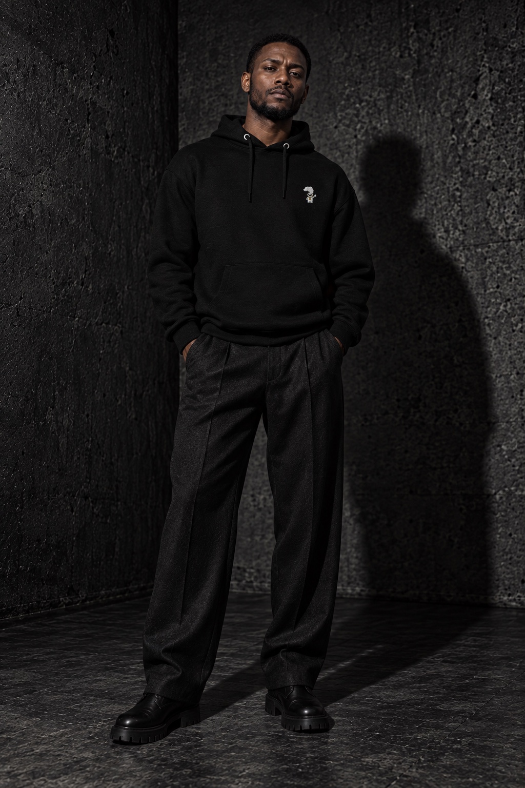 AI styling concept: adult man in a black Cosmic Chill embroidered hoodie, charcoal trousers and black boots