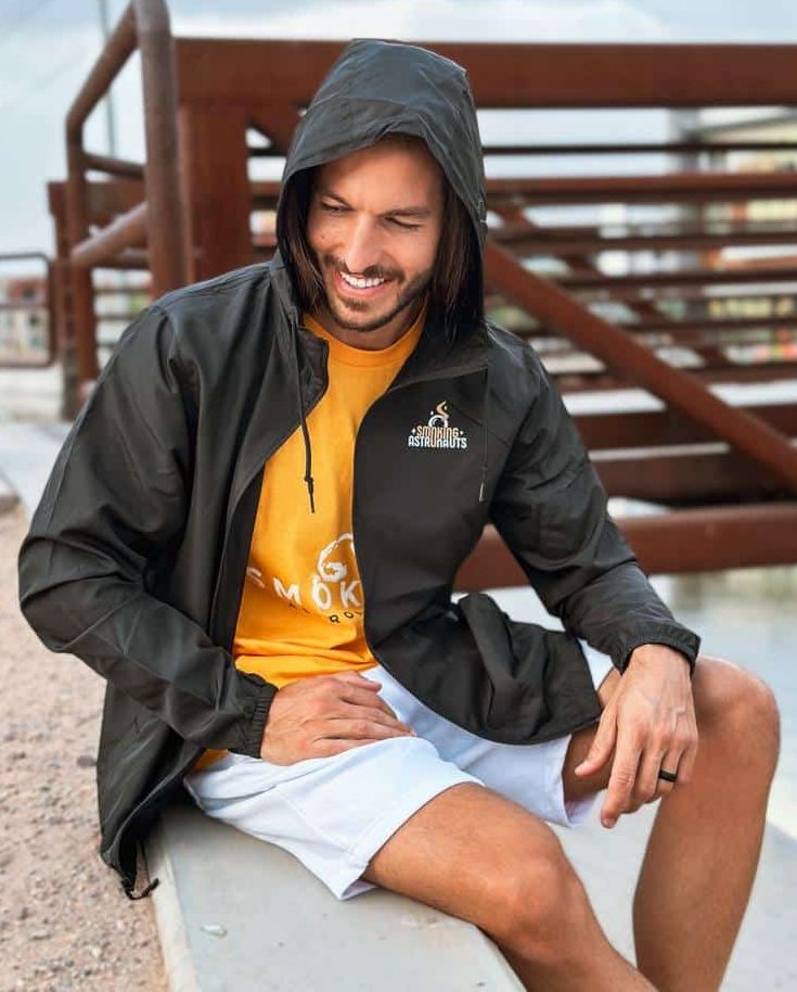 Theo wearing the original black Smoking Astronauts windbreaker over an orange shirt